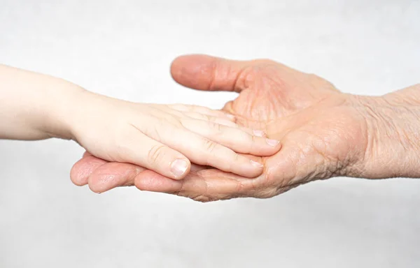 Jong baby kleinzoon hand ligt op de oude gerimpelde hand van oma. Rechtenvrije Stockafbeeldingen