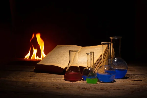 Средневековая алхимия и аптечная концепция со старой книгой и бутылками с лекарствами. Текст в книге не узнаваем — стоковое фото