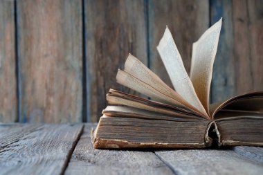 Ahşap bir arka planda antik bir kitabı açtı. Kitaptaki metin tanınabilir değil