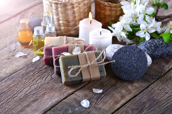 Ароматный спа фон с мылом ручной работы, ароматическими свечами, цветами, ароматическими маслами и камнями на деревянном фоне — стоковое фото