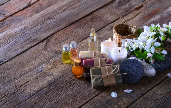 Aroma spa background with handmade soap, aroma candles, flowers, aromatic oils and stones on the wooden background
