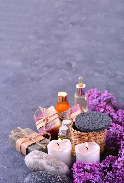 SPA still life with handmade soap, aroma candles, lilac flowers, aromatic oils and stones. — Stock Photo, Image