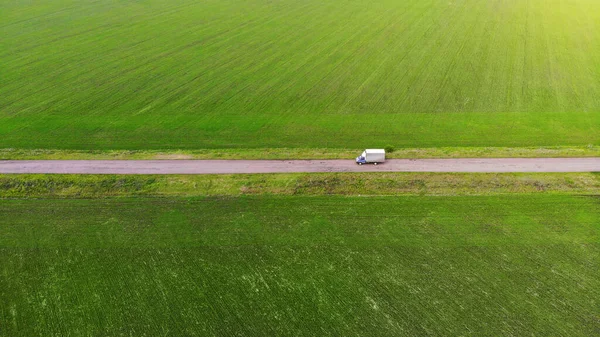 Vrachtwagen rijdt tussen de groene velden. Luchtfoto. Bekijk hierboven — Stockfoto