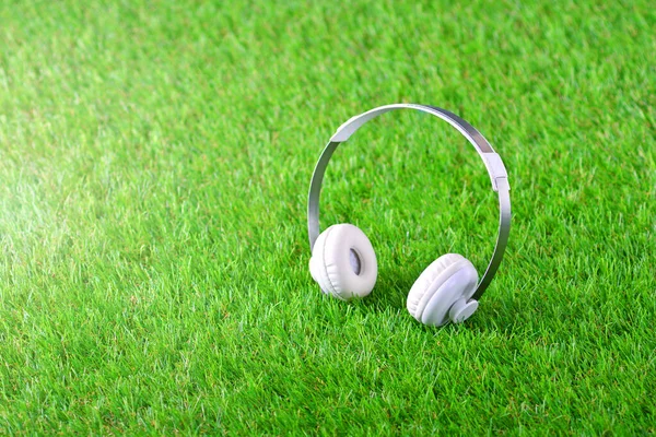 Białe słuchawki na zielonej sztucznej trawie — Zdjęcie stockowe