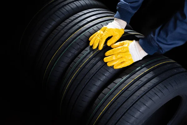 Depoda yeni lastikler var. İşçi bir lastik alır.