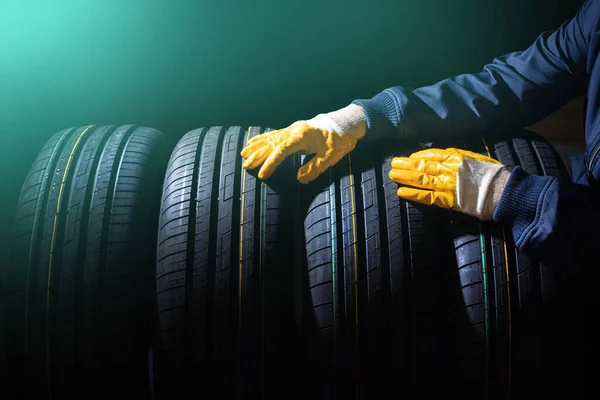 Reifenwechsel. Ein Satz neuer Reifen in den Händen eines Arbeiters. Getönt — Stockfoto