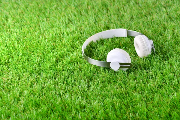 Białe słuchawki na zielonej sztucznej trawie . — Zdjęcie stockowe