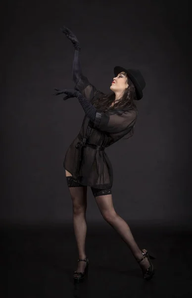 Hermosa joven bailando en túnica negra, guantes negros y sombrero negro . — Foto de Stock