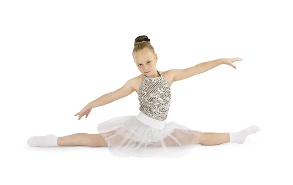 Ein kleines Mädchen im hellen Bühnenkostüm turnt auf weißem Hintergrund. — Stockfoto