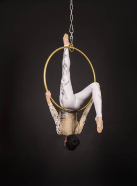 İnce, koyu saçlı kız - beyaz ve mavi takım elbiseli bir hava akrobat, bir hava halkası egzersizleri gerçekleştirir.