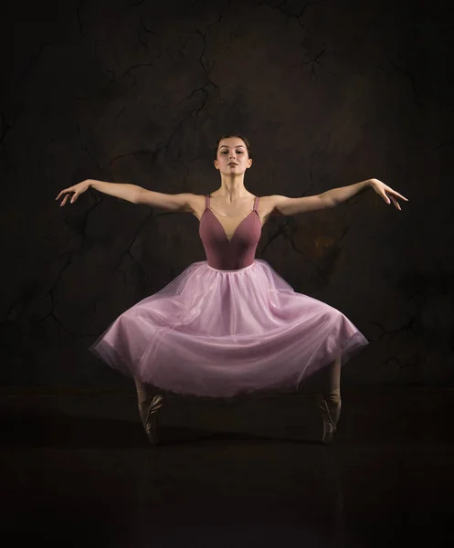 Uma menina esbelta em uma saia rosa e bege top dança balé . — Fotografia de Stock