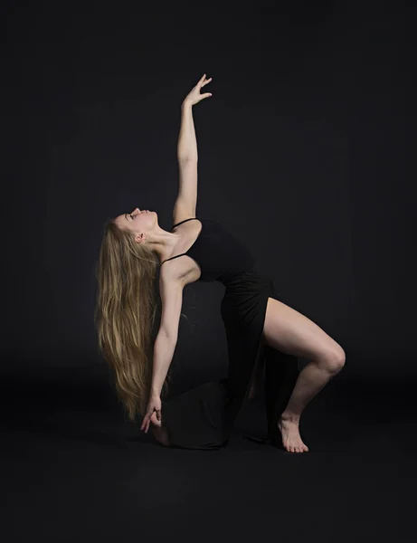 Uzun sarı saçlı siyah elbiseli bir kız modern bir bale yapıyor.. — Stok fotoğraf