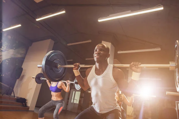 Passar ungdomar lyfta skivstång över deras huvuden fokuserade, arbetande ute i gym med andra människor — Stockfoto