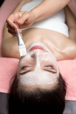 Güzellik salonunda maske takan güzel bir kadın. Fırçalı el