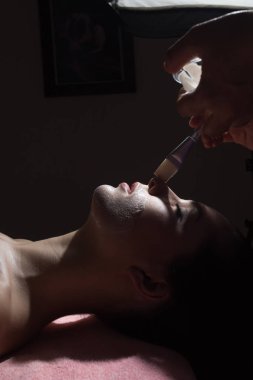 Spa kavramı. Genç kadın güzellik salonları, besin yüz maskesi ile kapatın. düşük anahtar fotoğraf