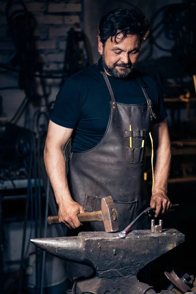 검은 대장장이가 모루에 용융 된 금속을 가루로 만들고 있다. — 스톡 사진