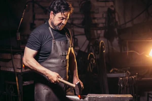 Pandai besi secara manual menempa logam cair di landasan di smithy dengan percikan kembang api — Stok Foto