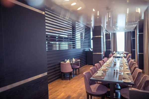 Half-Lighted hall in een loft-stijl in een Mexicaans restaurant met open keuken op de achtergrond. Tegenover de keuken zijn er houten tafels met multi-gekleurde stoelen en sofa's. Op de banken er — Stockfoto