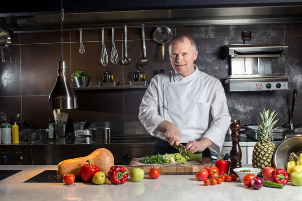 El chef corta las verduras en una comida. Preparando platos. Un hombre usa un cuchillo y cocina . — Foto de Stock