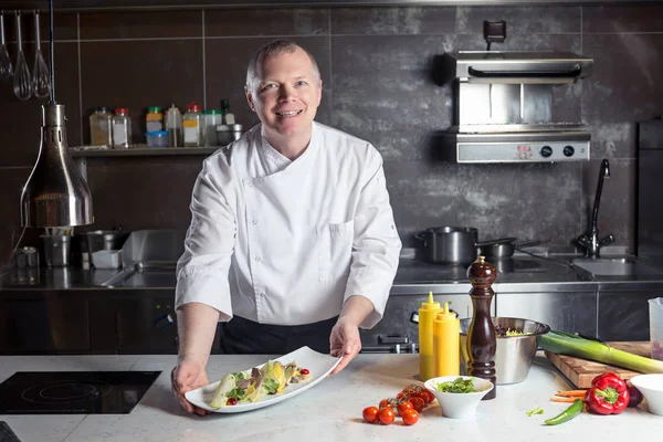 Chef-kok leunend op de teller met een schotel in een commerciële keuken — Stockfoto