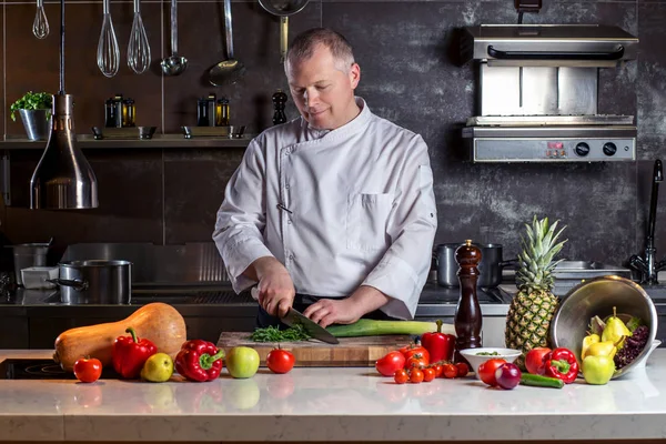 El chef corta las verduras en una comida. Preparando platos. Un hombre usa un cuchillo y cocina . — Foto de Stock