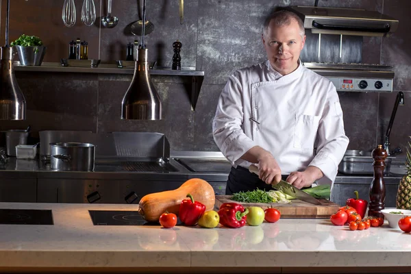 El chef corta las verduras en una comida. Preparando platos. Un hombre usa un cuchillo y cocina . — Foto de Stock