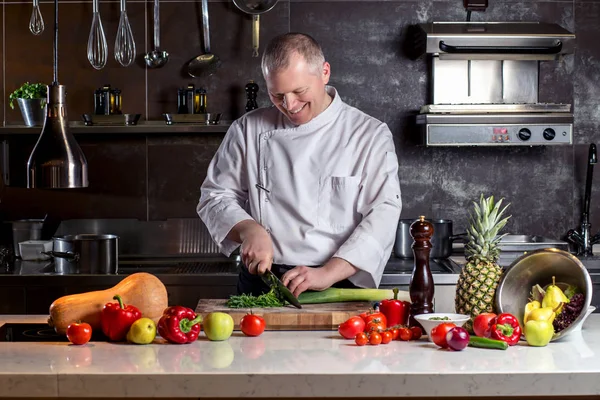 El chef corta las verduras en una comida. Preparando platos. Un hombre usa un cuchillo y cocina — Foto de Stock