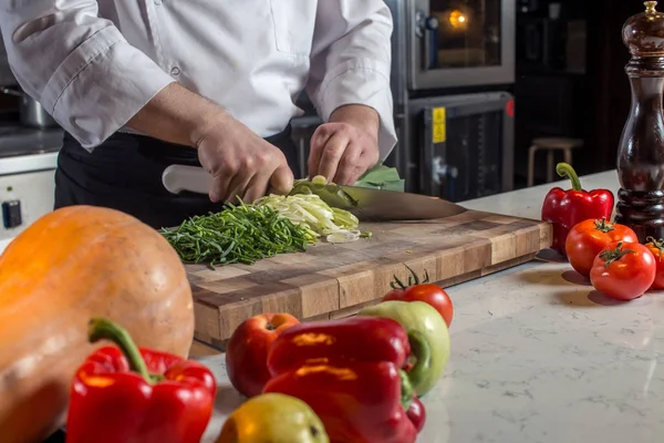 El chef corta las verduras en una comida. Preparando platos. Un hombre usa un cuchillo y cocina — Foto de Stock