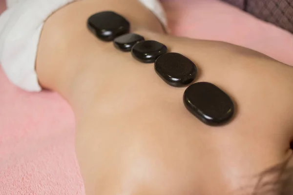 Donna ottenere massaggio con pietre calde nel salone spa. concetto di trattamento di bellezza. — Foto Stock