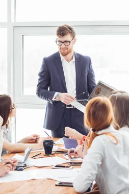 Girişim ekibi, modern parlak ofis içi beyin fırtınası, dizüstü bilgisayar ve tablet bilgisayar üzerine toplantı üzerine çalışıyor
