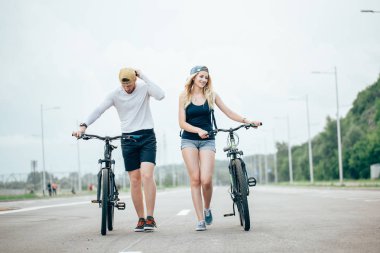 Genç çift Bisiklet birlikte yolda yürürken