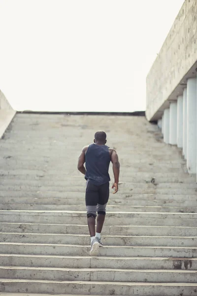 Вид ззаду чоловіка спортсмен біжить сходами зовні будівлі — стокове фото
