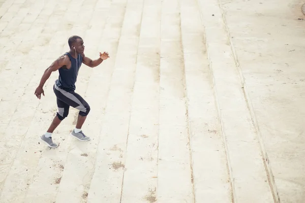 Male african athlete running up flight of stairs with speed — Stock Photo, Image