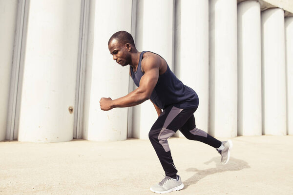Athlete man in running start pose on the city street. Sport tight clothes.