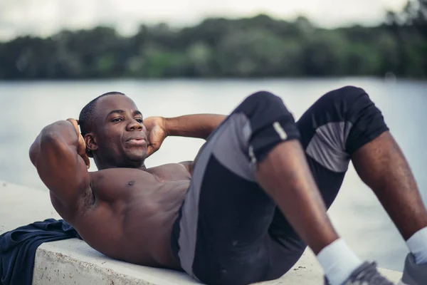 Sida porträtt av en ung svart man gör sit ups — Stockfoto