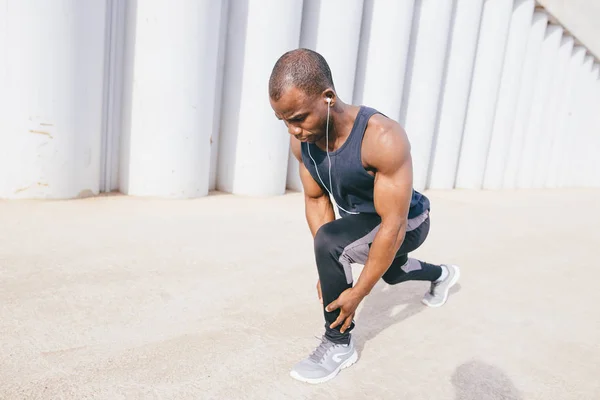 Чоловічий бігун у чорному спортивному одязі розтягує ноги перед ранковим тренуванням — стокове фото
