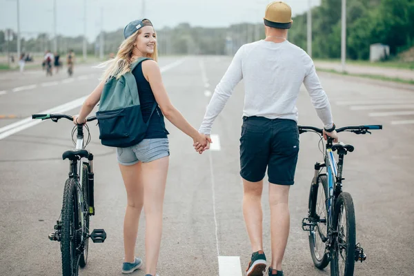 Genç çift Bisiklet birlikte yolda yürürken