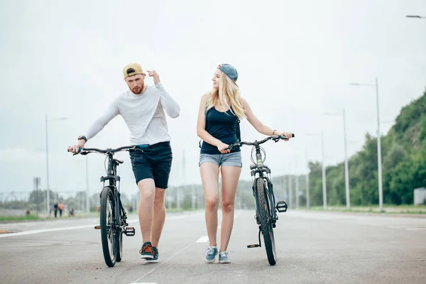 Mężczyzna i kobieta chodzić swoje rowery w dół drogi — Zdjęcie stockowe