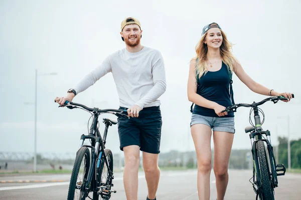 Jeune couple de vélos de marche ensemble sur la route — Photo