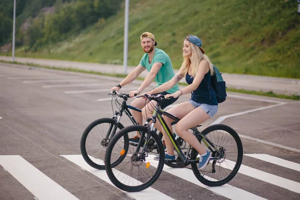 Pareja activa en un paseo en bicicleta por el campo en un día soleado — Foto de Stock