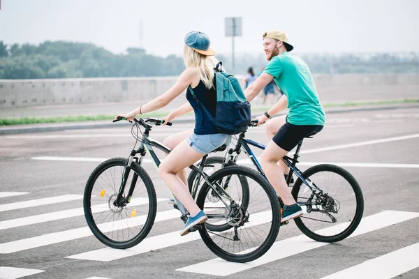 Visão traseira de um casal feliz andando de bicicleta segurando — Fotografia de Stock