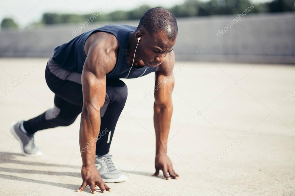 Athlete man in running start pose on the city street. Sport tight clothes.