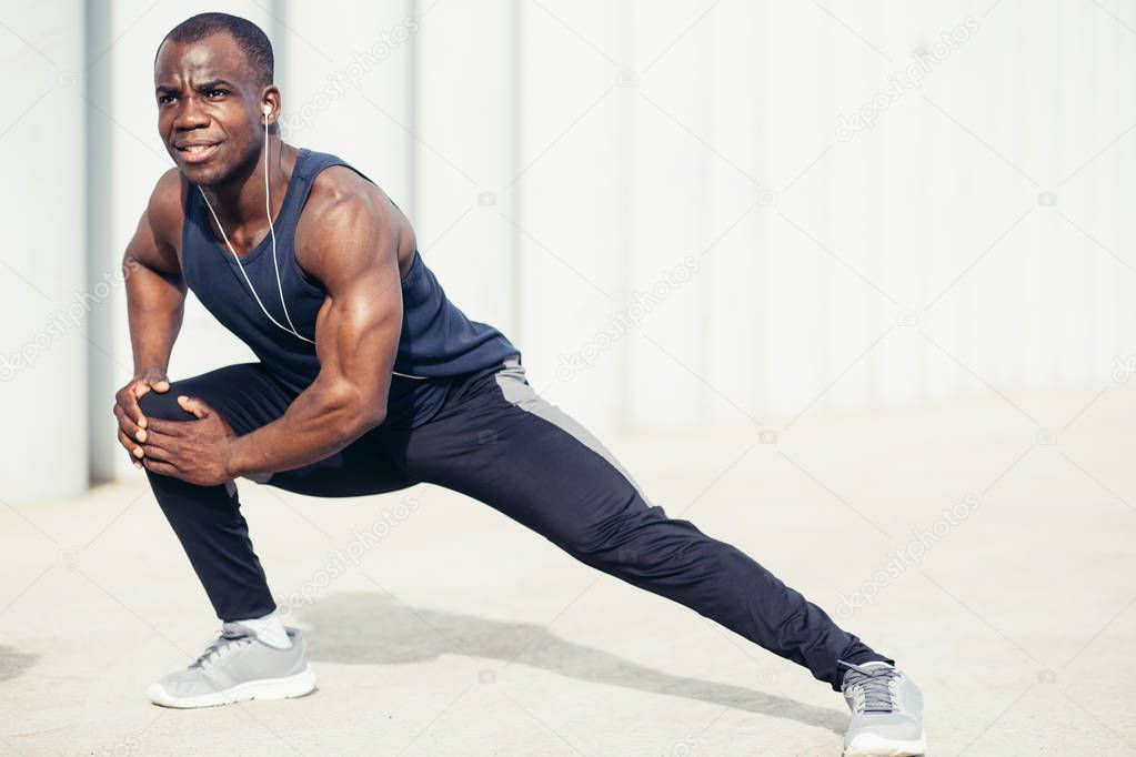 African man looking away with stretching his leg