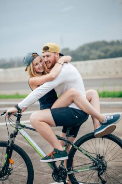 mutlu bir adam kız bisikleti onun çubuk üzerinde sahilde götürecek