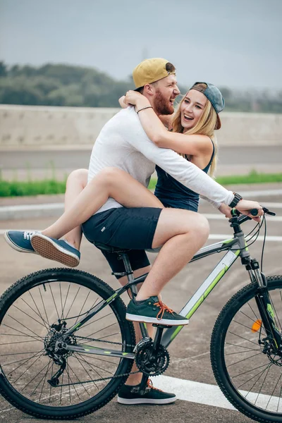 Szczęśliwy człowiek, dając dziewczyna windą na jego urządzenie miksujące rowerów na plaży — Zdjęcie stockowe
