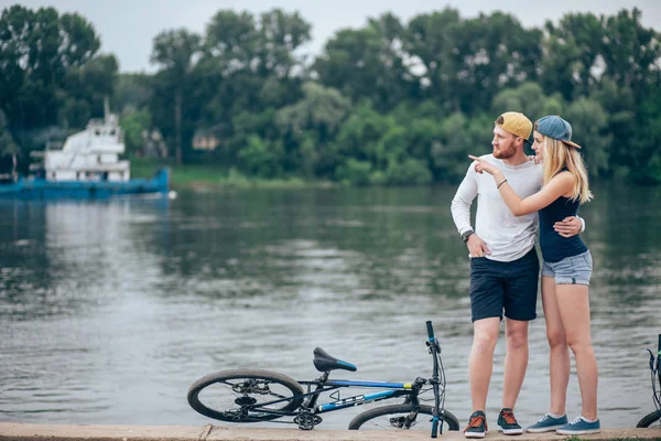 Gölde bir bisiklet ile bir tahta üzerinde dinlenme aşık Çift