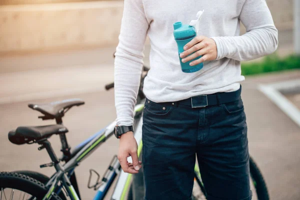 Велосипедист пьет воду над голубым небом на дороге — стоковое фото