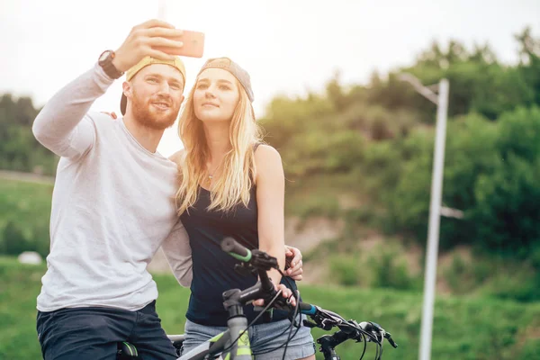 Casal feliz com bicicleta tirando selfie ao ar livre — Fotografia de Stock