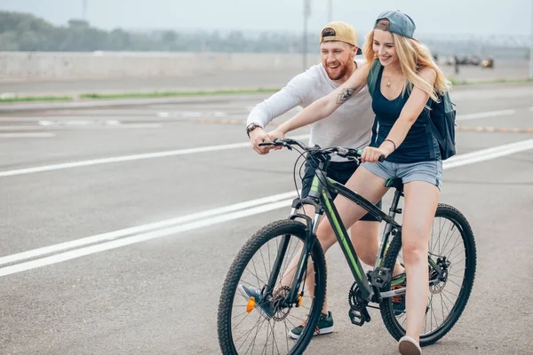 Mädchen auf dem Fahrrad, Kerl läuft. Junge bringt Mädchen Fahrradfahren bei. Morgenwiese. — Stockfoto