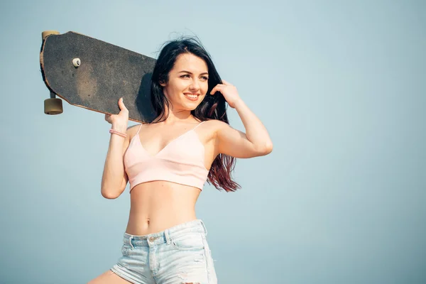 Retrato de mujer joven sosteniendo tabla larga en hombros cerca de las palmas en la playa . — Foto de Stock